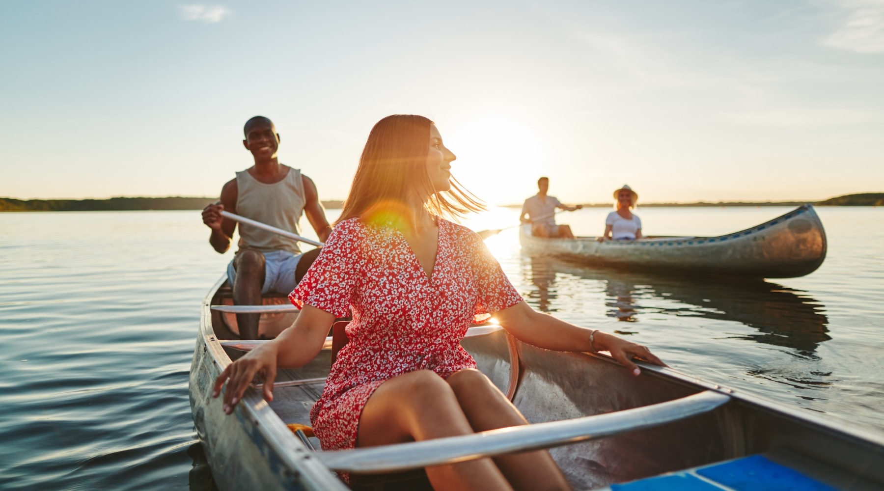 A group of people on boats with the sunset behind them